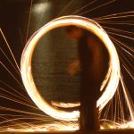 Ζογκλέρ δημιουργεί φωτεινό κύκλο περιστρέφοντας αλυσίδες με φωτιές σε εκδήλωση βάφτισης στην παραλία του Σουνίου.